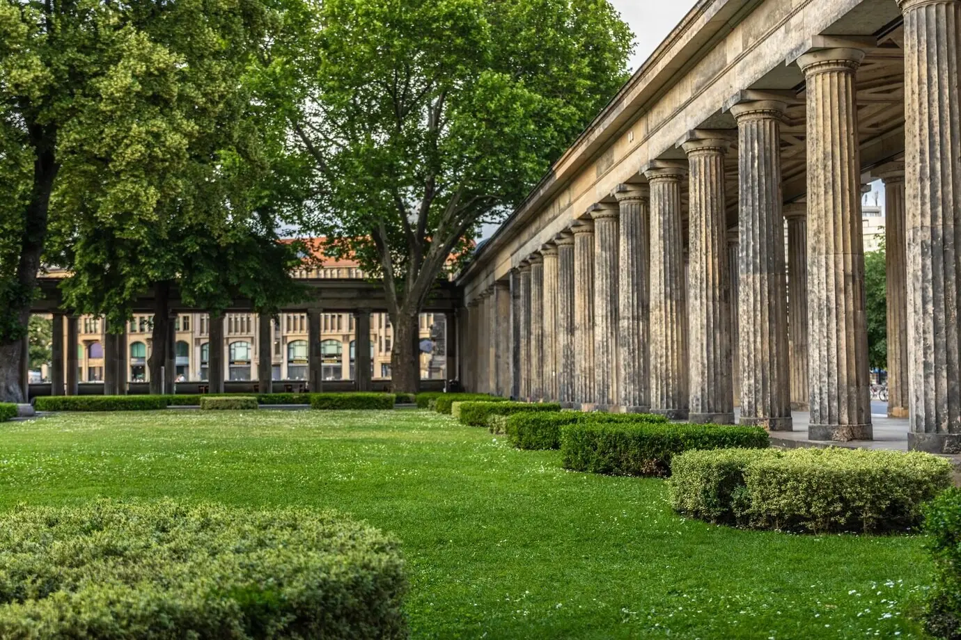 Antike Kolonnade im Stadtzentrum, umgeben von einem grünen Garten – architektonische Harmonie der Natur.